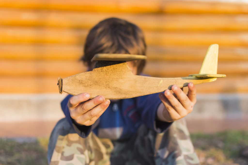 close up boy holding wooden aeroplane his hands